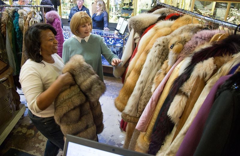Lynette Gamble (left) and Peggy Newfield look over the fur coats sold at an auction of the estate of Atlanta business executive Diane McIver.  She owned 137 fur coats.  January 14, 2017. STEVE SCHAEFER / SPECIAL TO THE AJC