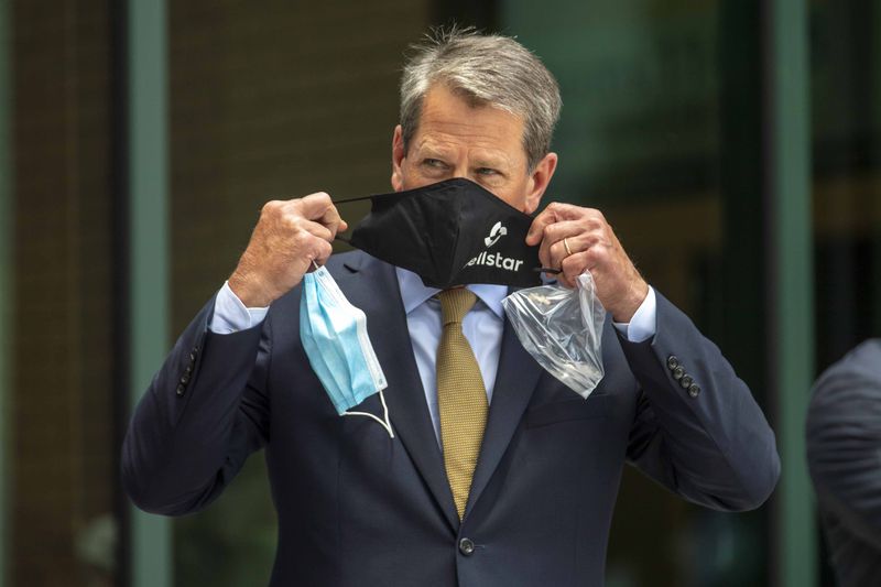 Upon arriving at the ribbon-cutting ceremony for the new Wellstar Kennestone Hospital Emergency Department building in Marietta on Thursday, Gov. Brian Kemp received a Wellstar mask. He switched the new mask with the one he had on, before the start of the event. (ALYSSA POINTER / ALYSSA.POINTER@AJC.COM)