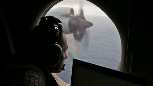 FILE - In this March 22, 2014 file photo, flight officer Rayan Gharazeddine scans the water in the southern Indian Ocean off Australia from a Royal Australian Air Force AP-3C Orion during a search for the missing Malaysia Airlines Flight MH370. A team of international investigators hunting for missing Malaysia Airlines Flight 370 said Tuesday, Dec. 20, 2016 it has concluded the plane is unlikely to be found in a stretch of the Indian Ocean search crews have been combing for two years, and may instead have crashed in an area farther to the north. (AP Photo/Rob Griffith, File)
