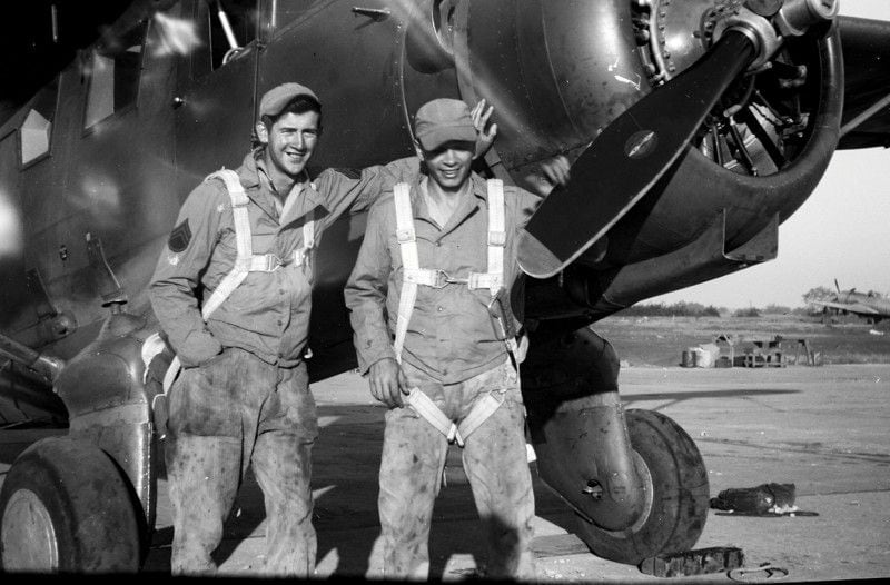 Staff Sgt. Jim Galloway, left, in greasy overalls and parachute.