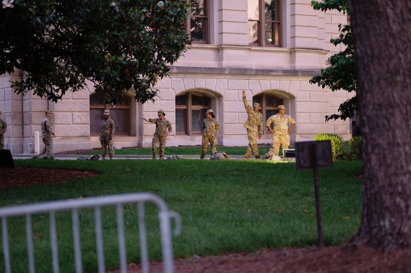 National Guard members stationed at the Capitol smile Saturday evening as they speak with demonstrators standing nearby.