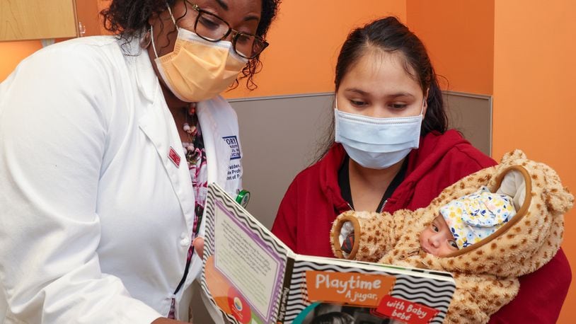 Pediatrician Dr. Terri McFadden encourages Maria Del Rosario to read to her baby, Camila Reyes Espinoza, during a visit to Children's Healthcare of Atlanta at Hughes Spalding.  PHIL SKINNER FOR THE ATLANTA JOURNAL-CONSTITUTION