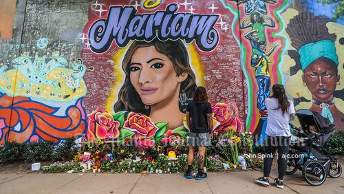 Maurice and Amber Gonzalez and their baby Maurice III stop at the mural of Mariam Abdulrab on Wylie Street, painted above a memorial still growing Monday morning. On Sunday, Atlanta police announced charges against DeMarcus Brinkley in Abdulrab's death.