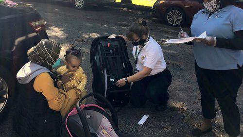 Scottdale Early Learning Parent Educator Tamra Davenport and a representative from Safe Kids DeKalb check car seats as part of SEL’s Parents as Teachers program. CONTRIBUTED