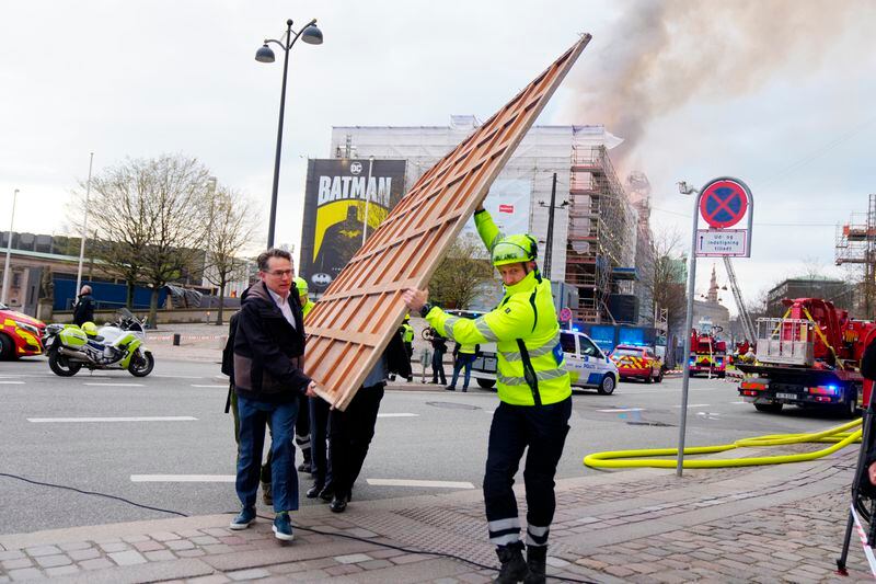 Former Danish Minister of Culture and current CEO of Danish Business, Brian Mikkelsen, left, assists with the evacuation of paintings from the Boersen burning in Copenhagen on Tuesday, April 16, 2024. A fire raged through one of Copenhagen’s oldest buildings on Tuesday, causing the collapse of the iconic spire of the 17th-century Old Stock Exchange as passersby rushed to help emergency services save priceless paintings and other valuables. (Ida Marie Odgaard/Ritzau Scanpix via AP)