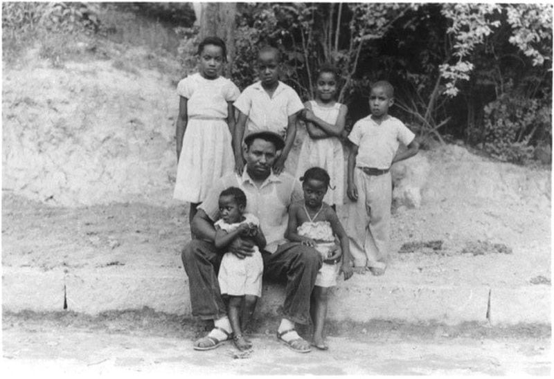Abe Thomas and six of his seven children outside of their Linnentown home in the 1950s. Hattie Thomas Whitehead, who is spearheading a campaign for reparations and recognition for the descendants of Linnentown, is standing with her arms crossed. Courtesy Hattie Thomas Whitehead.