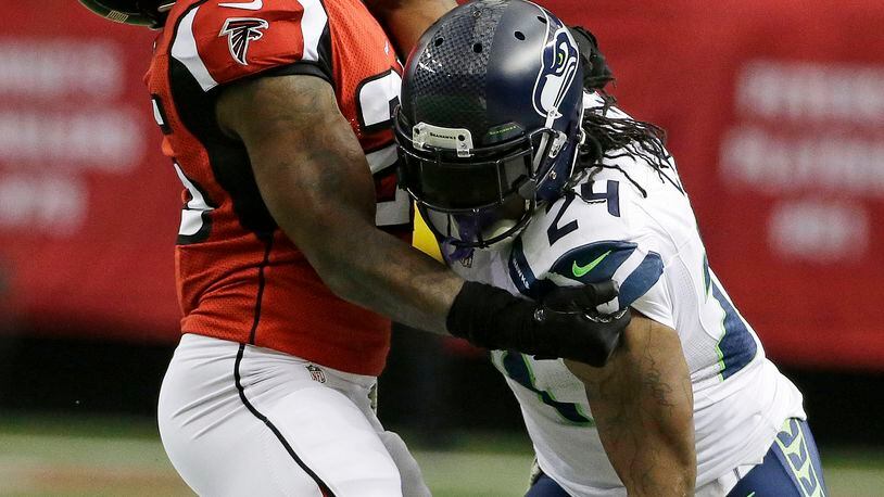 Seattle Seahawks running back Marshawn Lynch (24) strait arms Atlanta Falcons strong safety William Moore (25) during the first half of an NFL football game, Sunday, Nov. 10, 2013, in Atlanta. (AP Photo/David Goldman)