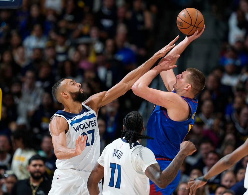 Minnesota Timberwolves center Rudy Gobert, left, goes up to block a shot by Denver Nuggets center Nikola Jokic, right, as Timberwolves center Naz Reid (11) looks on in the second half of Game 1 of an NBA basketball second-round playoff series Saturday, May 4, 2024, in Denver. (AP Photo/David Zalubowski)