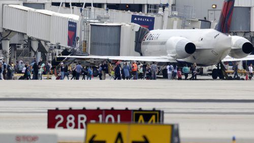 People stand on the tarmac at the Fort Lauderdale-Hollywood International Airport after a shooter opened fire inside the terminal, killing several people and wounding others before being taken into custody, Friday, Jan. 6, 2017, in Fort Lauderdale, Fla. (AP Photo/Lynne Sladky)