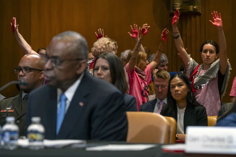 Protestors opposed to the Israel-Hamas war are escorted out as Secretary of Defense Lloyd Austin, left, speaks during a hearing of the Senate Appropriations Committee Subcommittee on Defense on Capitol Hill, Wednesday, May 8, 2024, in Washington. (AP Photo/Mark Schiefelbein)