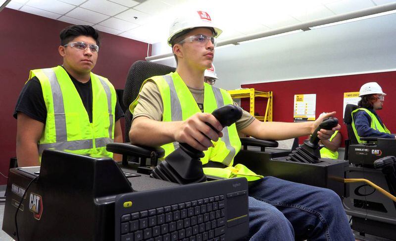 Kevin Hunt, 17, a junior at Jordan Vocational High School, center, works on a CAT Simulator as part of the school’s Heavy Equipment Operator Training Program. (Photo Courtesy of Mike Haskey mhaskey@ledger-enquirer.com)