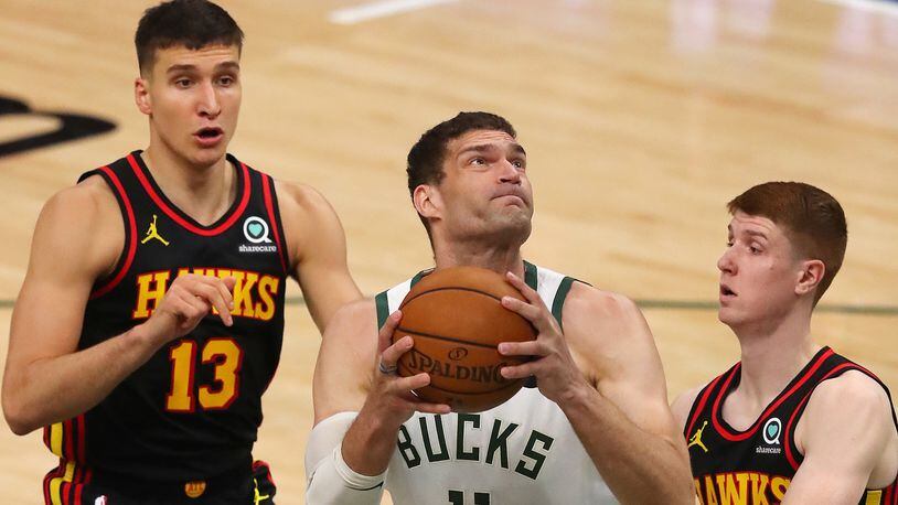 Hawks guards Bogdan Bogdanovic (left) and Kevin Huerter can't stop Bucks center Brook Lopez from going to the basket for two of his 33 points during the first quarter in game 5 of the NBA Eastern Conference Finals on Thursday, July 1, 2021, in Milwaukee.