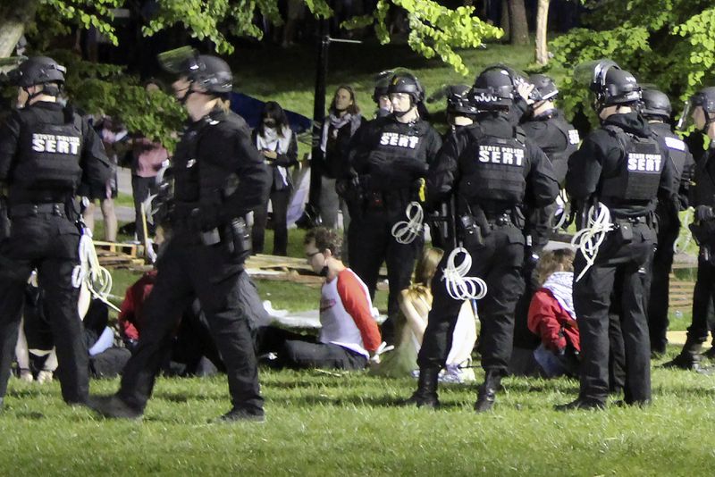 Members of law enforcement place people in handcuffs, Wednesday, May 8, 2024, on the University of Massachusetts Amherst campus, in Amherst, Mass. Police moved in Tuesday night to break up an encampment at the school in what appeared in video to be a hours-long operation as dozens of police officers in riot gear systematically tore down tents and took protesters into custody. The protesters established the tent encampment to demonstrate against the war in Gaza. (Kalinka Kornacki via AP)