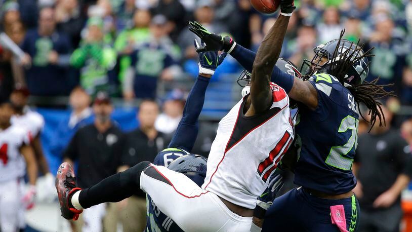 Seattle Seahawks cornerback Richard Sherman, right, and Earl Thomas (obscured) break up a pass intended for Falcons wide receiver Julio Jones (11) on Sunday, Oct. 16, 2016, in Seattle. The Seahawks beat the Falcons 26-24. (AP Photo/Elaine Thompson)