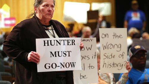 Collene Haskamp stands with her sign while more protesters demand the resignation of Tommy Hunter, the District 3 leader that recently called U.S. Rep. John Lewis a “racist pig” on Facebook, during the Gwinnett County Board of Commissioners public hearing Tuesday. Curtis Compton/ccompton@ajc.com