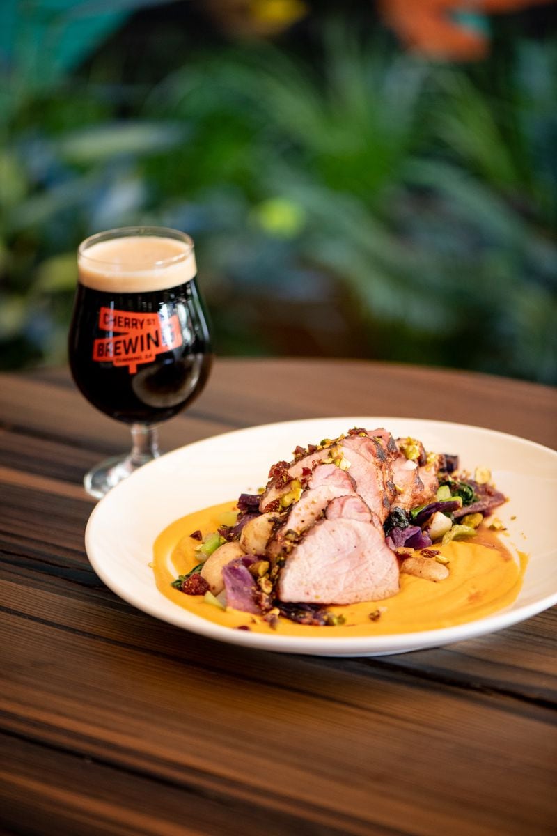 Leon's Full Service Pork Loin With Sweet Potato Puree, Roasted Vegetables and Pistachio Cranberry Crumble is paired with Coconut Porter from Cherry Street Brewing. (Mia Yakel for The Atlanta Journal-Constitution)