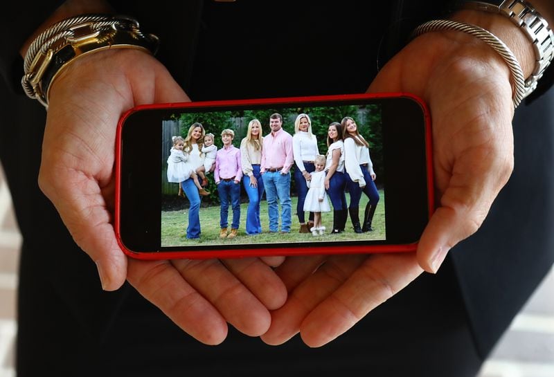 Venus Morris Griffin shows off a recent family photo of herself with her children Julia (from left) holding her twins Gisele and Vendela, Charles, Sydney, John IV, herself, Hannah Lou, Alexis, and Elle at the family home in Augusta. Curtis Compton / Curtis.Compton@ajc.com”