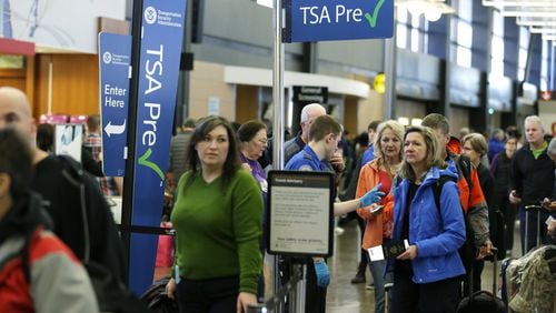 Travelers authorized to use the Transportation Security Administration’s PreCheck expedited security line at Seattle-Tacoma International Airport in Seattle have their documents checked by TSA workers. Massive lines at airports have now led to a backlog of people trying to enroll in trusted traveler programs. Waits to join PreCheck or Global Entry are months long in some cities. (AP Photo/Ted S. Warren, File)