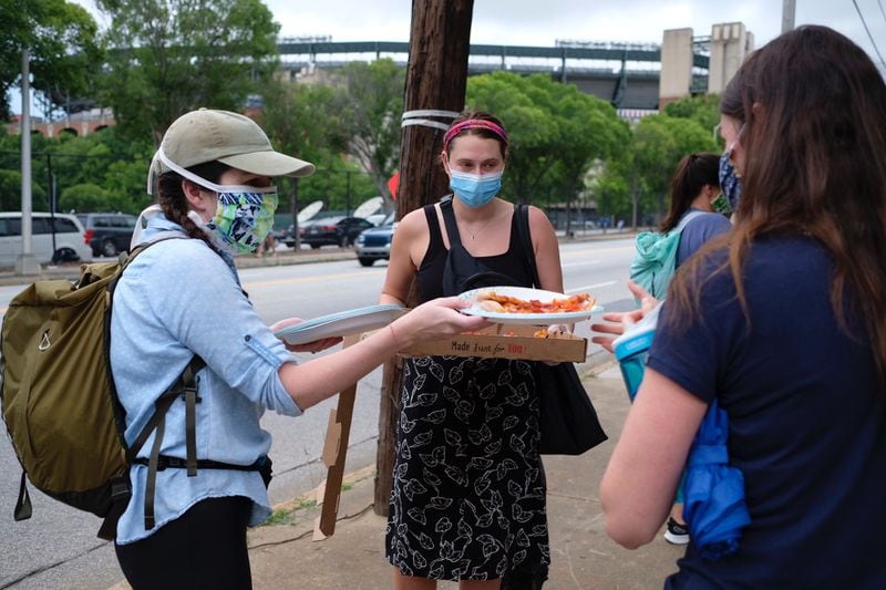 Meghan Shakar, left and Alexis Goldman with Pizza Protest ATL handing out free pizza to sustain people during their wait to vote at the fanplex across from GSU stadium. (Ben Gray for The Atlanta Journal-Constitution)