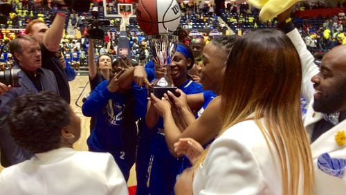 Americus-Sumter players and coaches receive the championship trophy after defeating Troup 66-52 in the Class AAAA girls final on Friday, March 6, 2020, at the Macon Centreplex.