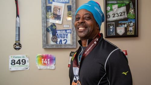 Eugene Hardy Jr. stands with some of the running medals he has won recently in his apartment in Stone Mountain. He was a combat veteran, was formerly homeless, jobless and battling addition. He camped out in the woods near high school stadiums so he could run around the track and focus on getting his life back in order. Two VA programs are now helping him with a home and a job. (Photo by Phil Skinner)