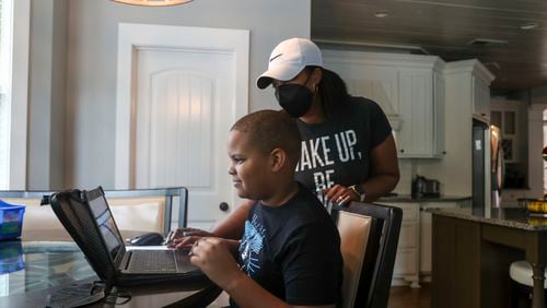 Timber Ridge Elementary School fourth grader Aiden Zeigler, 9, gets help from his mother, Davene Sawyer, while working on his school lessons at the kitchen table in McDonough. Schools across the metro area such Timber Ridge have reverted temporarily in the past month to virtual learning because of coronavirus breakouts. (Alyssa Pointer/Atlanta Journal Constitution)