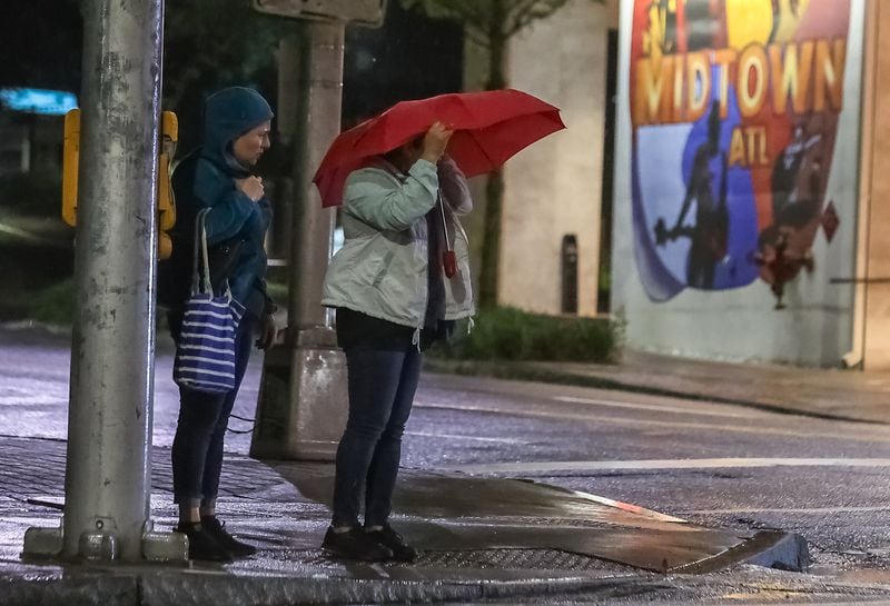 Atlantans are braving the cool, rainy conditions as they cross West Peachtree Street in Midtown early Friday morning.