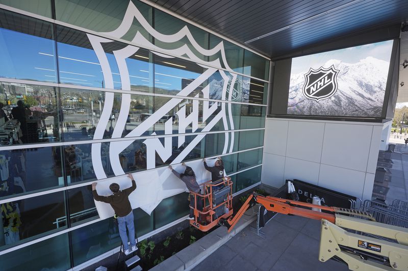 FILE - Workers put up signs celebrating the awarding of a new NHL team to Utah at the Delta Center Thursday, April 18, 2024, in Salt Lake City. It may look like an NHL team has just fallen into Salt Lake City's lap. But local organizers say the Arizona Coyotes' relocation to Utah is the product of a yearslong effort to beckon professional hockey and other elite sports to the capital city. The move marks a coming-of-age moment for Salt Lake City as a pro sports hub in the Mountain West. (AP Photo/Rick Bowmer, File)