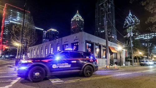 An Atlanta police patrol car drives by the Traffik Kitchen and Cocktails nightclub on the corner of Crescent Avenue and 12th Street, where two people were shot multiple times when someone opened fire early Friday. (John Spink / John.Spink@ajc.com)