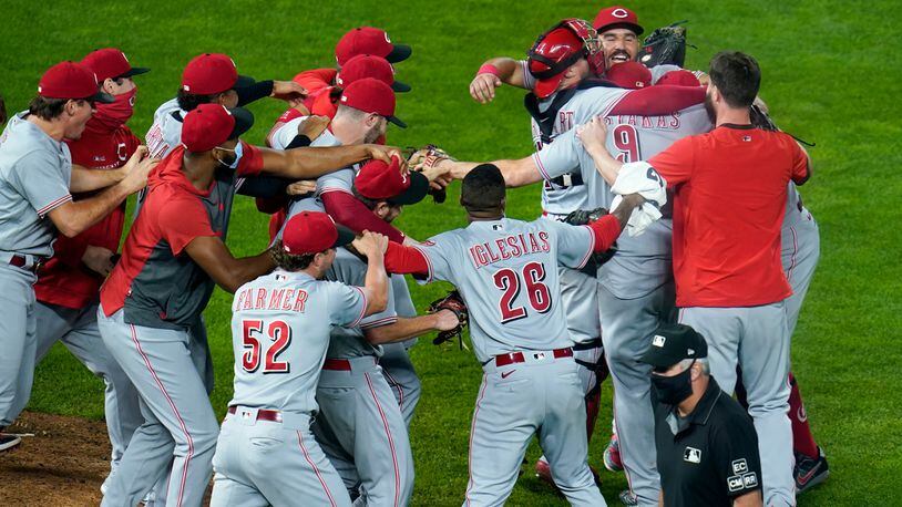 Cincinnati Reds players pour onto the field to celebrate with pitcher Wade Miley after the Reds clinched a playoff berth with a 7-2 over the Minnesota Twins 7-2 in a baseball game, Friday, Sept. 25, 2020, in Minneapolis. (AP Photo/Jim Mone)