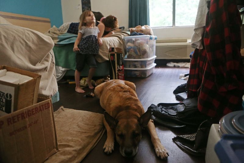 One of the Schroeder family’s three dogs lies on the floor while Elizabeth Schroeder watches television. CHRISTINA MATACOTTA / CHRISTINA.MATACOTTA@AJC.COM