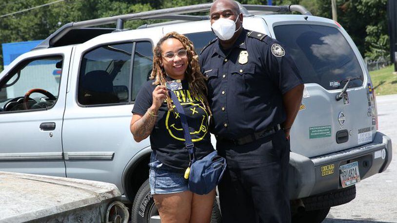 A police officer poses with a local woman as the Atlanta Police Department distributes 1,000 Kroger gift cards of $50 each donated by media mogul Tyler Perry.