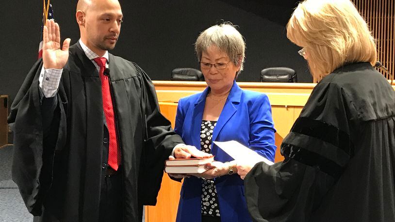 Ramon Alvarado (left) is sworn in as a Gwinnett County Recorder's Court judge on Monday by State Court Judge Emily Brantley (right) as his mother, YuSun Alvarado, looks on. Alvarado is the first Hispanic judge in Gwinnett County's history. TYLER ESTEP / TYLER.ESTEP@AJC.COM