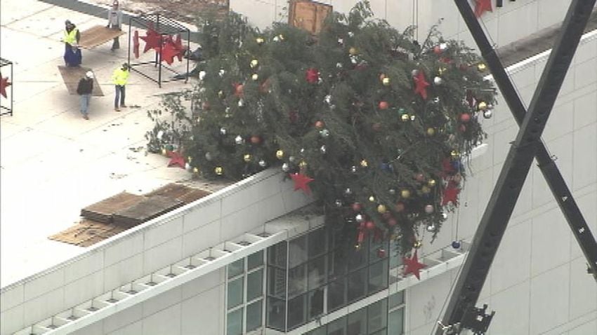 Crane buckles, leaving Christmas tree hanging off roof