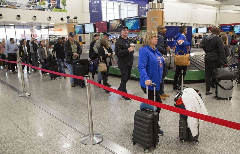 Kim LaFleur (CQ from Connecticut) waits for a friend as multiple security lines at Hartsfield-Jackson International Airport ran across the atrium then snaked through baggage claim in both domestic terminals on Monday February 4th, 2019. Official expected over 100,00 travelers to pass through the airport today. (Photo by Phil Skinner)