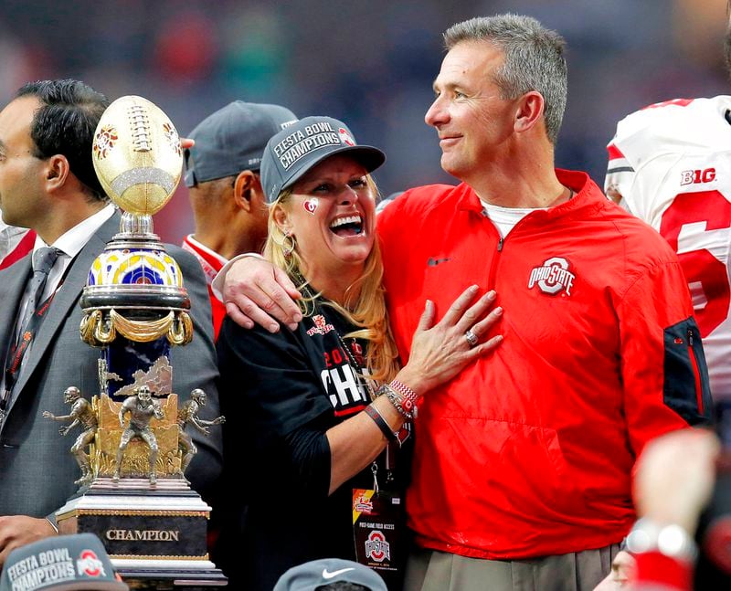 FILE - In this Jan. 1, 2016, file photo, Ohio State head coach Urban Meyer hugs his wife, Shelley, after their 44-28 win over Notre Dame in the Fiesta Bowl NCAA college football game, in Glendale, Ariz. Ohio State placed Meyer on paid administrative leave Wednesday, Aug. 1, 2018, while it investigates claims that his wife knew about allegations of abuse against former Buckeyes assistant Zach Smith, who was fired last week. (AP Photo/Rick Scuteri, File)