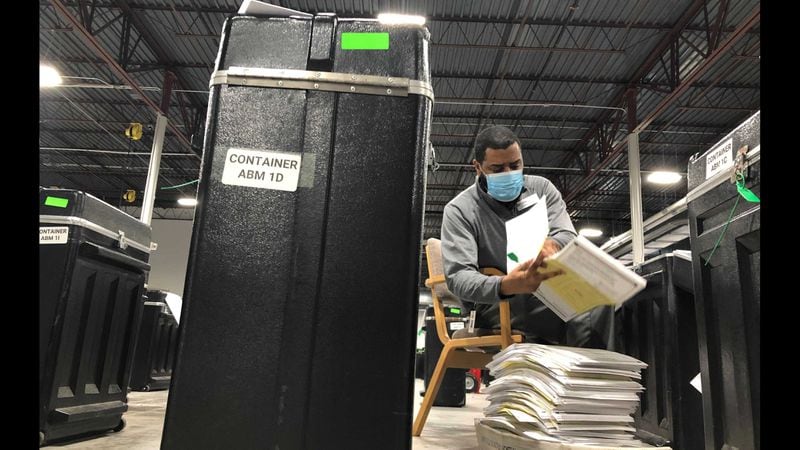 Gwinnett County employee Kareem Briscoe pulls batches of votes from a bin as he reconciles a log sheet with the batches on Sunday, Nov. 15, 2020. Christopher Quinn/cquinn@ajc.com.