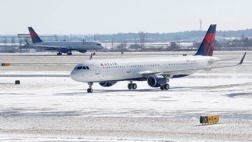 A Delta jet pushes through last week’s snowfall at Hartsfield-Jackson International Airport. BOB ANDRES /BANDRES@AJC.COM