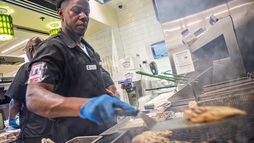 Marcus Bell (center) cooks chicken breasts at Hartsfield Jackson Atlanta International Airport. AJC File Photo