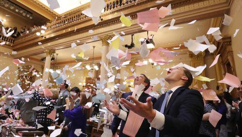 Jared Williams, right, throws a large pile of paper in the air next to his father, state Sen. Michael Williams, R-Cumming, as the Georgia General Assembly’s 2018 session came to a close early Friday. PHOTO / JASON GETZ