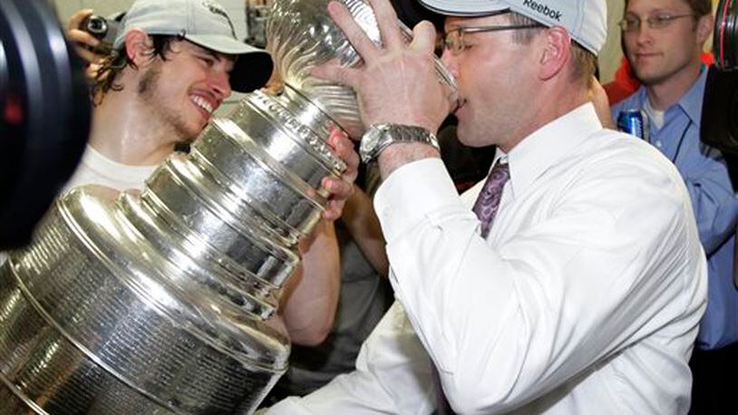 FILE - In this June 12, 2009, file photo, Pittsburgh Penguins' captain Sidney Crosby, left, helps Pittsburgh Penguins head coach Dan Bylsma drink champagne from the Stanley Cup after the Penguins beat the Detroit Red Wings 2-1 to win Game 7 of the NHL hockey Stanley Cup finals, in Detroit. Michael Schuckers, a statistics professor at St. Lawrence University in northern New York, said it�s also difficult to gauge the impact of a coach, unless there�s something like a team that�s relatively static and the only change made is the coach. �When the Penguins won the Stanley Cup, you can look at how the Penguins were under (current Montreal Canadiens coach Michel) Thierren (27-25-5) and under (Dan) Bylsma (18-3-4),� Schuckers said. �It's a clear break in terms of the team playing much better under Bylsma.� (AP Photo/Paul Sancya, File)