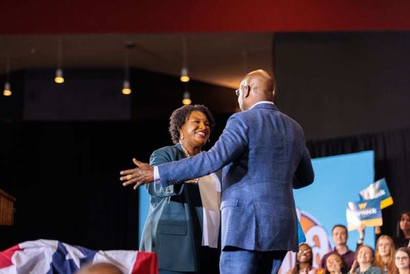 Democratic gubernatorial candidate Stacey Abrams greets U.S. Sen. Raphael Warnock at a voting rally Friday with former President Barack Obama. While Abrams trails Republican Gov. Brian Kemp in the newest Atlanta Journal-Constitution poll by 7 points, Warnock appears to be the beneficiary of some Republicans' choice to split their ticket at the expense of GOP candidate Herschel Walker. (Arvin Temkar / arvin.temkar@ajc.com)