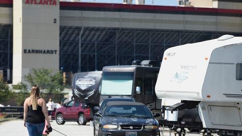 Chelsea Roberson, of Cape Coral, Fla., walks her dog near her parked RV at the Atlanta Motor Speedway, Friday, Sept. 8, 2017, in Hampton, Ga. Over 50 cameras and RV's are sheltering at the speedway from South Ga., South Carolina, and Florida. (AP Photo/Mike Stewart)