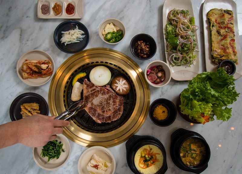  Banchan, tradtional Korean side dishes, surround the in-table grill at ARI Korean Steakhouse. / CONTRIBUTED BY HENRI HOLLIS