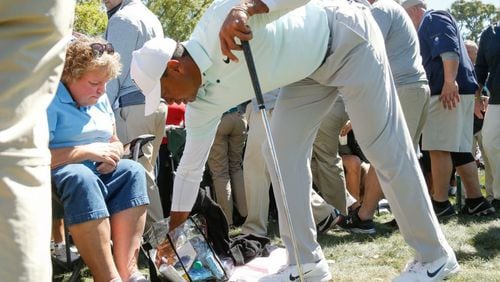 Tiger Woods removes his ball from the handbag of Marianna Cousins after hitting his second shot on the ninth hole during the second round of the Valspar Championship.