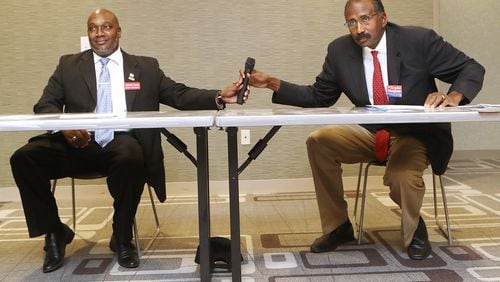 Candidates for the DeKalb County Commission Greg Adams, left, and Randal Mangham share a microphone while answering questions on how best to move the county forward during a debate at the Tucker-Reid H. Cofer Library on Nov. 29. Curtis Compton/ccompton@ajc.com