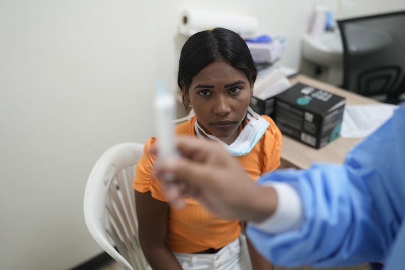 A patient looks at a birth control injection at a Doctors without Borders medical clinic in Putucual, Venezuela, Wednesday, Jan. 10, 2024. A group of women and teenage girls visited the medical clinic in eastern Venezuela where a community health worker taught them how to use an IUD, condoms and birth control pills correctly and about HPV infections. (AP Photo/Matias Delacroix)