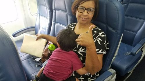Milagros Cruz, a case manager from the Hall County office of the Georgia Division of Family and Children Services, holds a boy during a flight to Honduras Monday where he and his brothers were reunited with their mother.