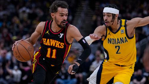 Atlanta Hawks guard Trae Young (11) drives on Indiana Pacers guard Andrew Nembhard (2) during the first half of an NBA basketball game in Indianapolis, Sunday, April 14, 2024. (AP Photo/Michael Conroy)