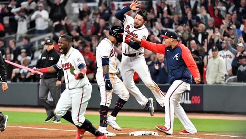 Braves catcher Travis d'Arnaud jumps onto left fielder Eddie Rosario after Rosario bought in the game-winning run a single in the ninth inning of Game 2 of the NLCS Sunday, Oct. 17, 2021, at Truist Park in Atlanta. The Braves won 5-4 to take a 2-0 lead in the series. (Hyosub Shin / Hyosub.Shin@ajc.com)